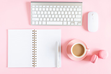 Women's office desk. Notebook, keyboard, cup of coffee, macaron on pastel pink background. Flat lay, top view, copy space