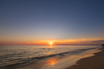 Naklejka na ściany i meble Vivid beautiful sunset and sunrise sky reflection on sea beach wave.