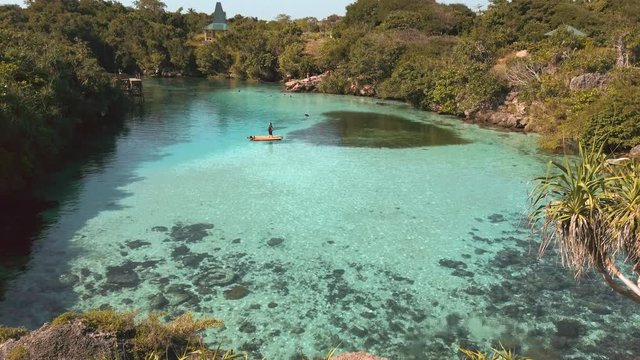 Tilt shot of Weekuri Lake, Sumba, surrounded by trees, on a sunny day