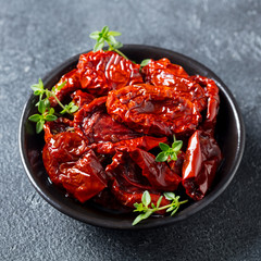 Sun dried tomatoes with fresh herbs and spices. Slate background. Close up. Top view.