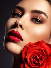 Beautiful young fashion woman with red lipstick. Pretty model with flower.