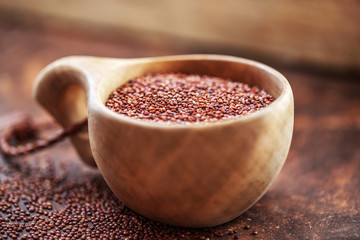 Red quinoa grains. Seeds of red quinoa - Chenopodium quinoa, in wooden cup  