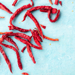 Dry red peppers on a blue background with copyspace, overhead square shot