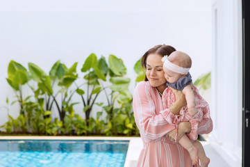 Mother standing near the pool with her baby