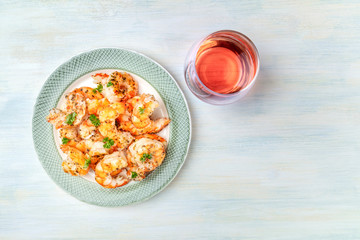 Cooked shrimps, shot from the top on a rustic wooden background with a glass of rose wine and a...