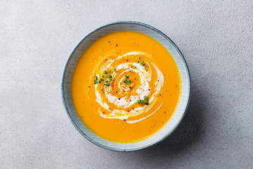 Pumpkin and carrot soup with cream on grey stone background. Top view. - 289662852