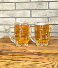 Two glasses of light beer on wooden table. 