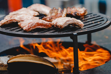 Pork ribs and steak cooked on grill, open fire street food festival