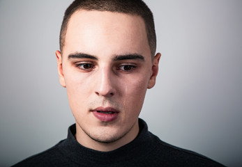 Obraz premium Unhappy crying young man with dropping tears on the face. Closeup studio portrait on grey background. Negative emotional concept