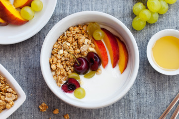 Healthy breakfast. Fresh granola, muesli with yogurt, fruits and berries on grey background. Top view.