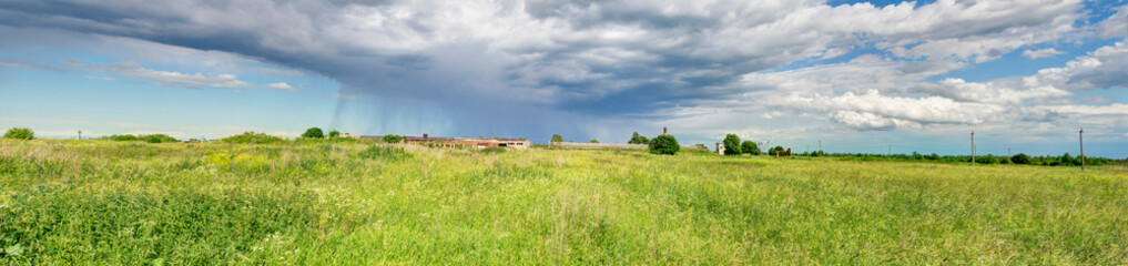 Fototapeta na wymiar Rain clouds over the green field panorama