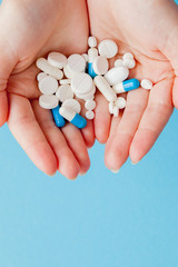 Woman's holding cupped hand full of pills, view from above