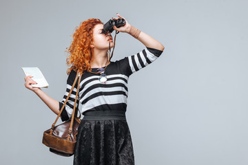 red head tourist girl looks through binoculars