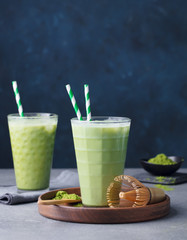 Matcha green tea ice latte with matcha powder and bamboo whisk. Grey background. Copy space.