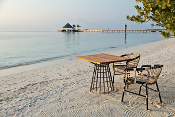 Elegant table and two chairs on sandy beach, romantic vacations background