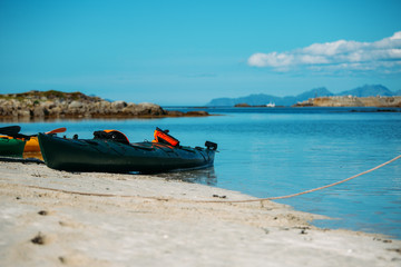 Photo of colorful kayaks on sandy seashore, blue sky in Norway on summer.