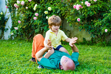 Cute child boy hugging his grandfather. Happy senior man Grandfather with cute little boy grandson playing and looking at camera. Grandfather with Son and Grandson having Fun in Park.