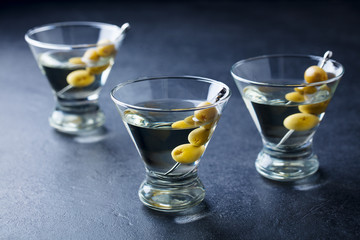 Martini cocktail with green olives. Slate background. Close up.