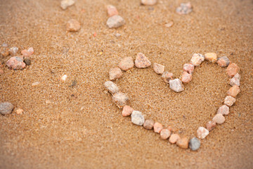 Fototapeta na wymiar Heart on the beach. Heart of stones in the sand. Pattern heart, a symbol of love. Valentine's Day, wedding, congratulations - photo background, concept