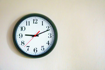 Black clock showing 9.10 o'clock on the wall with Copy Space. Soft focus process.