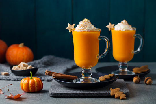 Pumpkin latte with spices. Boozy cocktail with whipped cream on slate board. Grey background. Copy space.