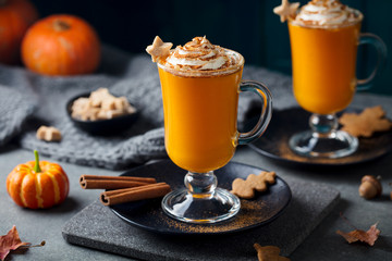 Pumpkin latte with spices. Boozy cocktail with whipped cream on slate board. Grey background. Close up.