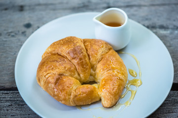 Croissants topped with honey on a white plate