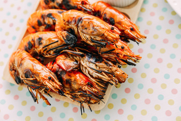 Top view of Thai grilled prawns (shrimps) in the shell in wooden plate served with Thai style spicy sauce.