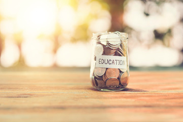 Coins in jar on wood table in the public park.money saving education concept.retro vintage color tone.