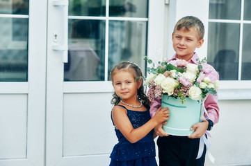 A boy and a girl holding a bouquet of flowers . Beautiful children with roses