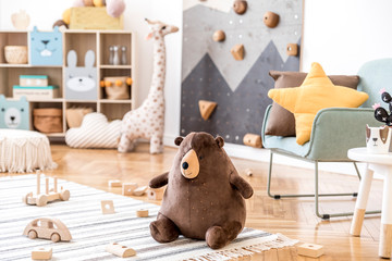 Modern scandinavian interior design of childroom with mint armchair, climbing wall for kids, design furnitures, soft toys, teddy bear and cute children's accessories. Stylish kidroom decor. Template. - obrazy, fototapety, plakaty