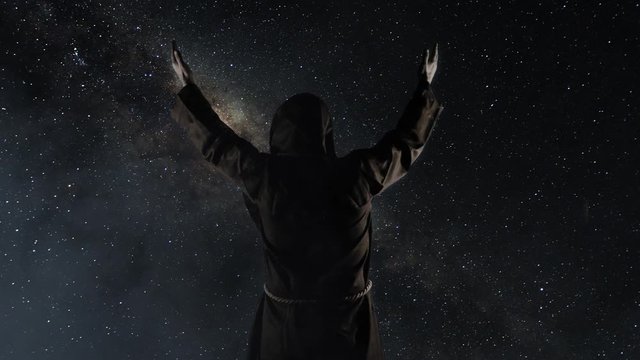 Silhouette of a monk in a cassock against a starry sky