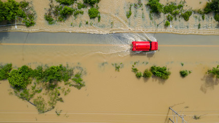 Aerial top view of Flooded the village and Country road with a red car, View from above shot by...