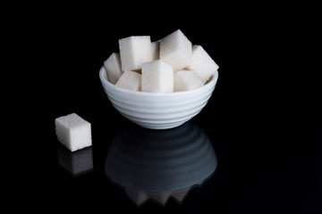 Sugar cubes in sugar bowl on black background