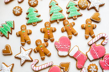 Obraz na płótnie Canvas Handmade festive gingerbread cookies in the form of stars, snowflakes, people, socks, staff, mittens, Christmas trees, hearts for xmas and new year holiday on white paper background