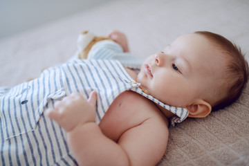 Close up of adorable baby boy lying on bed and waiting for his mother to pick him up.