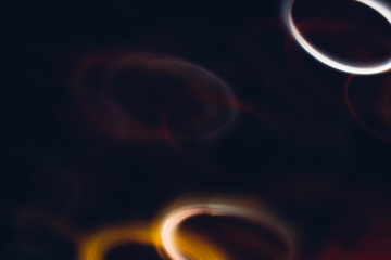 Defocused glowing rings. Blur illuminated circles. Dark abstract art background.