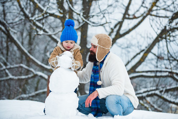 Christmas holidays. Happy winter time. Father and son making snowman.