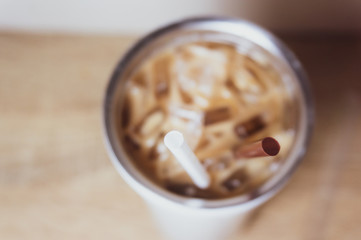 Brown and white straw in iced coffee. Stainless steel cup