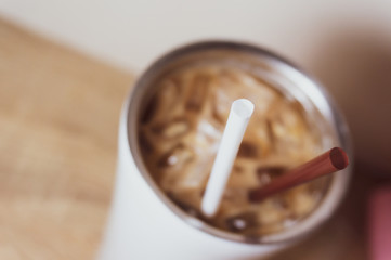 Brown and white straw in iced coffee. Stainless steel cup