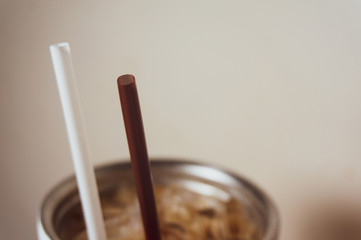 Brown and white straw in iced coffee. Stainless steel cup
