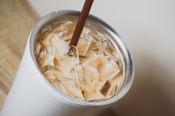 a bottle of iced coffee and brown plastic straw on wood surface table