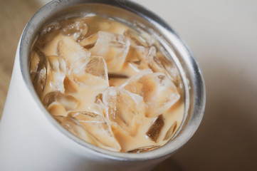 iced coffee and brown plastic straw in white bottle stainless steel cup