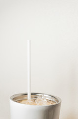 white plastic straw and cup of iced coffee stainless steel cup