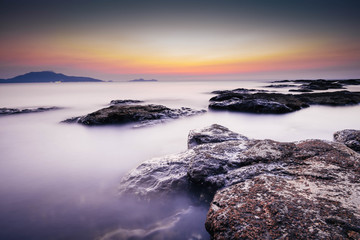 Fototapeta na wymiar Long exposure landscape photo of sea with rocks during sunset. Milky smooth water. 