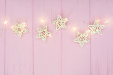 Christmas lights garland with stars border over pink background. Flat lay, copy space