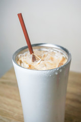 iced coffee and brown plastic straw in white stainless steel bottle
