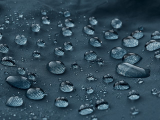 Rain water droplets on blue fiber waterproof fabric. Blue background.