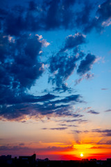 Blue sky with white clouds at sunset, town in the distance
