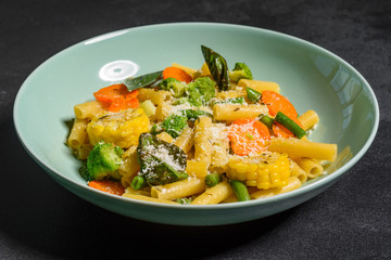 Delicious fresh warm paste sprinkled with cheese parmesan with broccoli, corn, carrots and other vegetables. Vegetarian food
